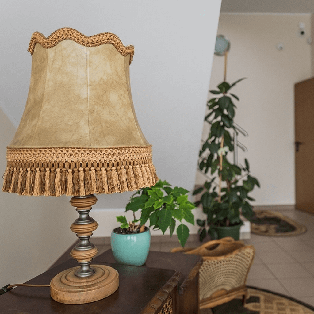 Jauki globos namų interjero detalė – stalinė lempa su augalu šalia