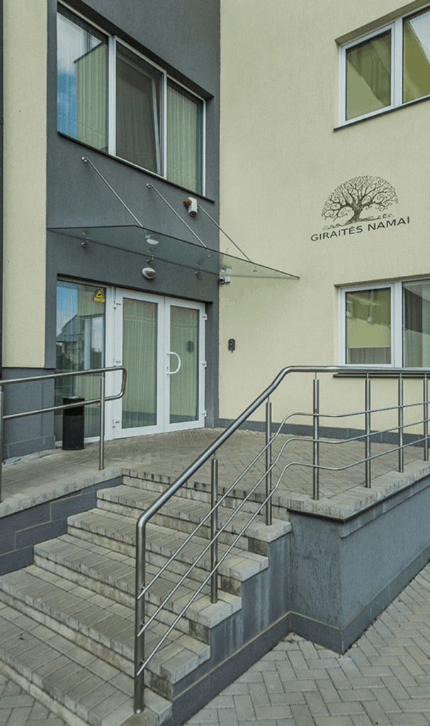 Pastato „Giraitės namai“ įėjimas su stiklinėmis durimis, laiptais ir pandusu su turėklais