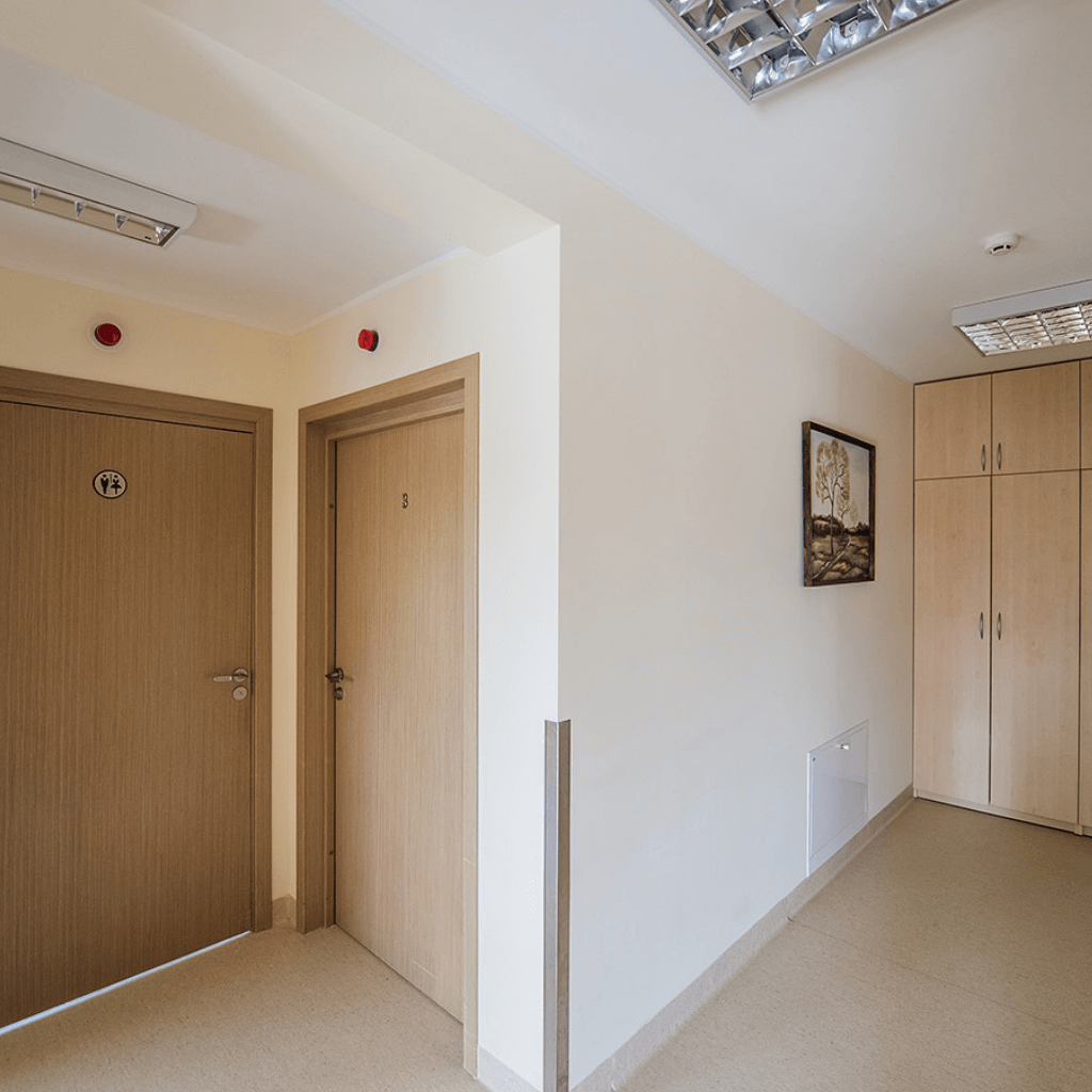 Šviesus biuro ar įstaigos koridorius su medinėmis durimis, spintomis ir minimalistiniu interjeru