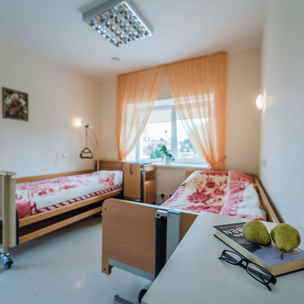 Šviesus globos namų kambarys su dviem lovomis, reguliuojamais turėklais ir dideliu langu